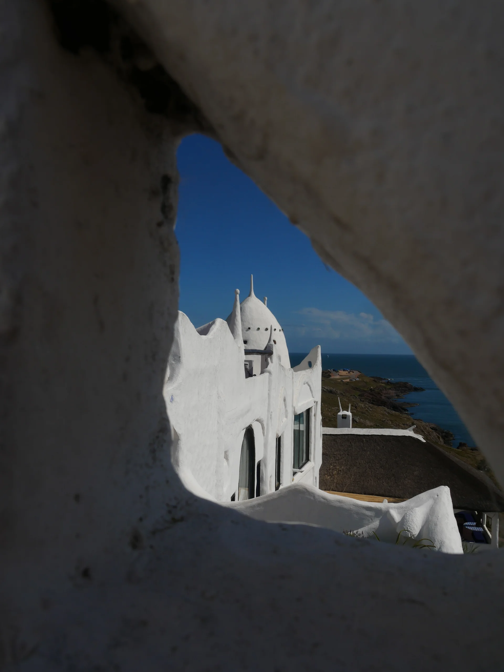 Vistes cap al Río de la Plata i les cúpules blanques de Casapueblo a través d'una obertura a la paret de l'edifici.