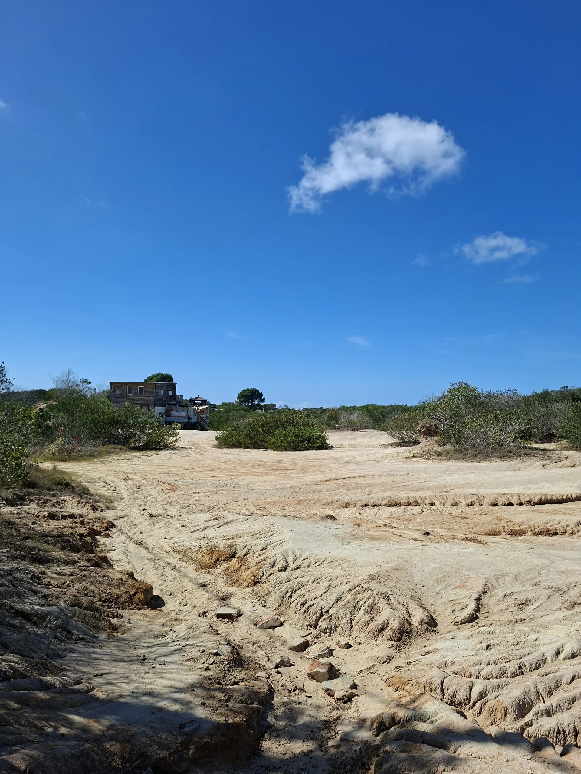 Ampli paisatge desèrtic i sorrenc amb vegetació baixa que envolta la rústica cabana de fusta a Punta Rubia, prop de La Pedrera, Uruguai.