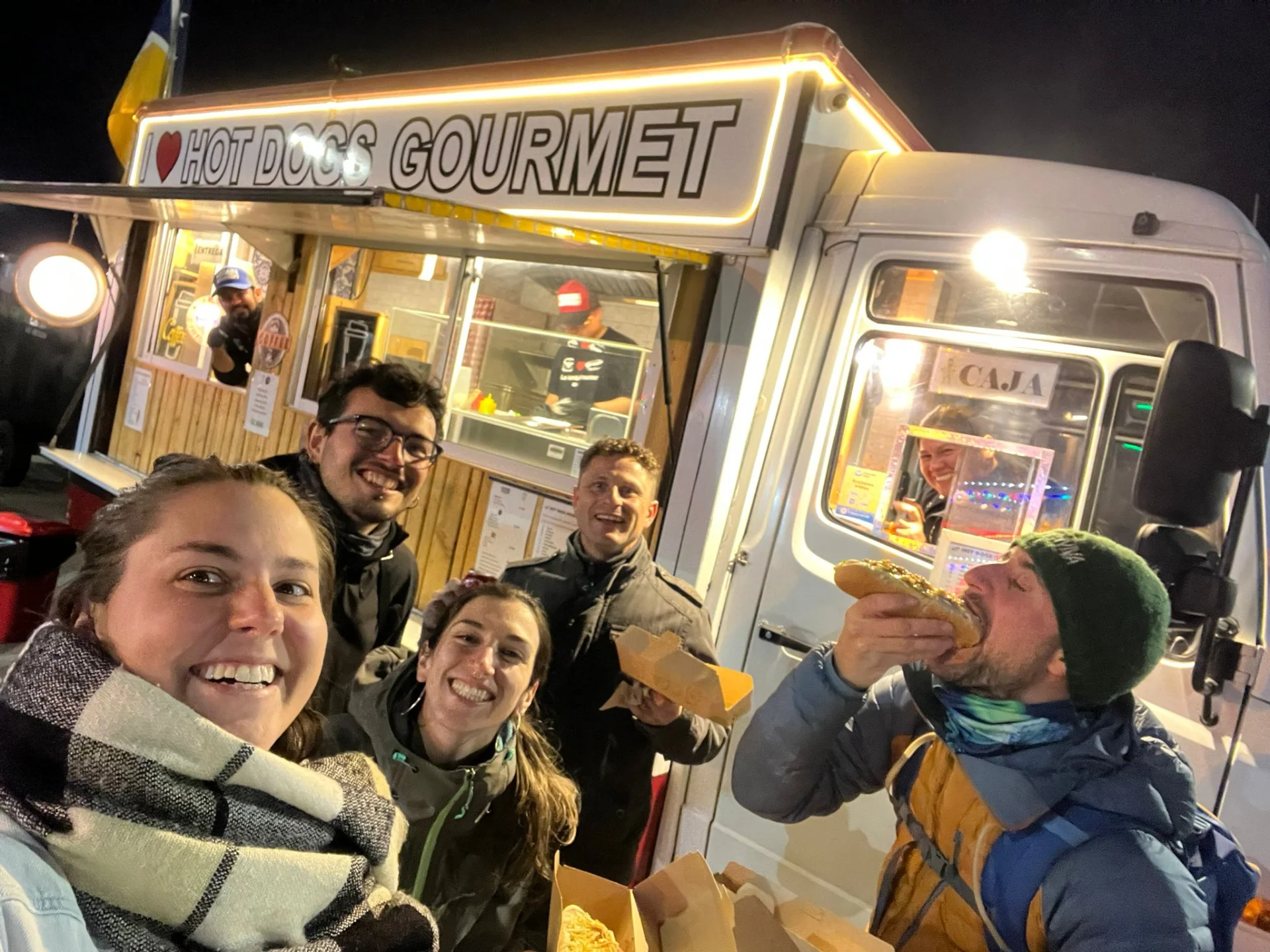 Un grup d'amics es fa una foto de nit davant un foodtruck.