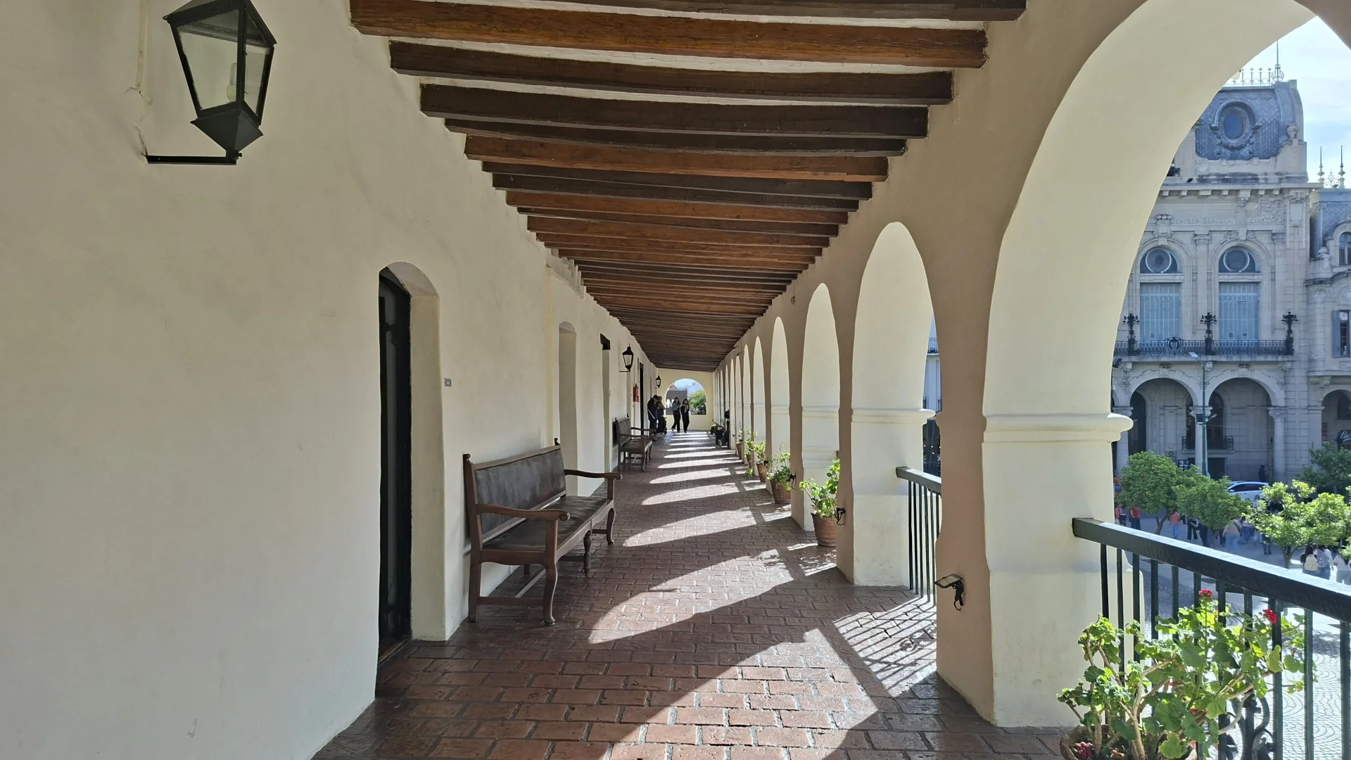 Perspectiva de la galeria superior d'arcs del Cabildo històric de Salta, amb bigues de fusta al sostre, terra de rajoles de terracota, bancs de fusta al costat de la paret emblanquinada i vistes a la Plaza 9 de Julio i a l'arquitectura senyorial dels voltants.